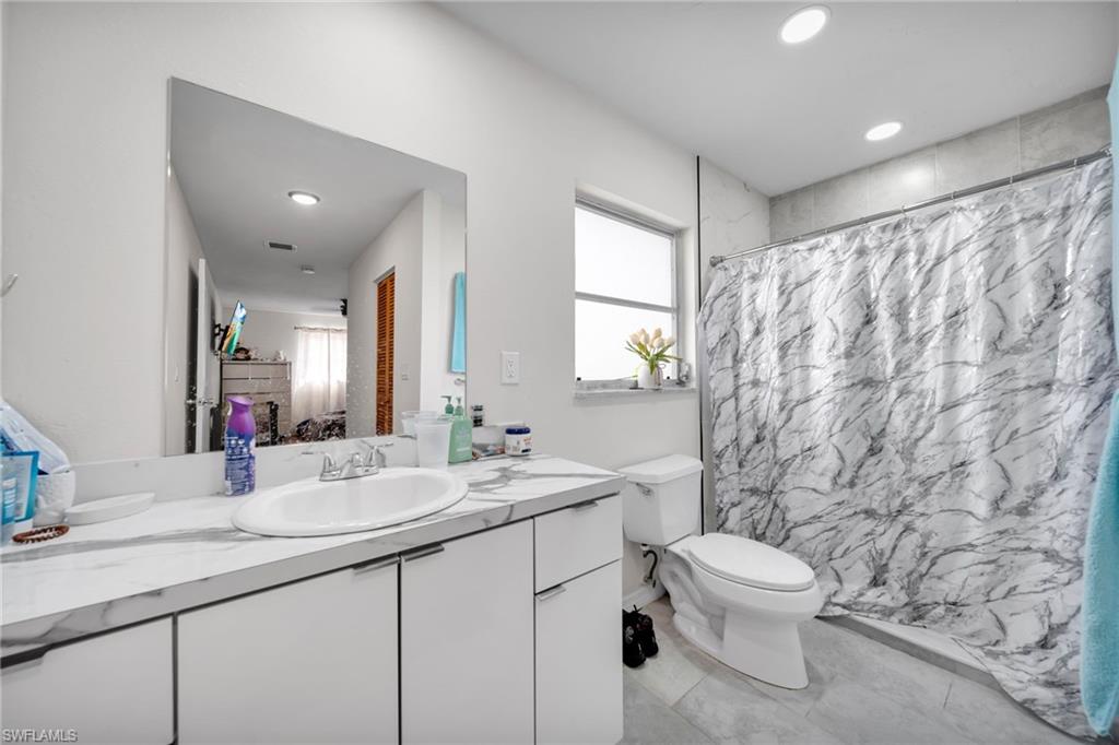 Full bathroom with vanity, toilet, curtained shower, and recessed lighting