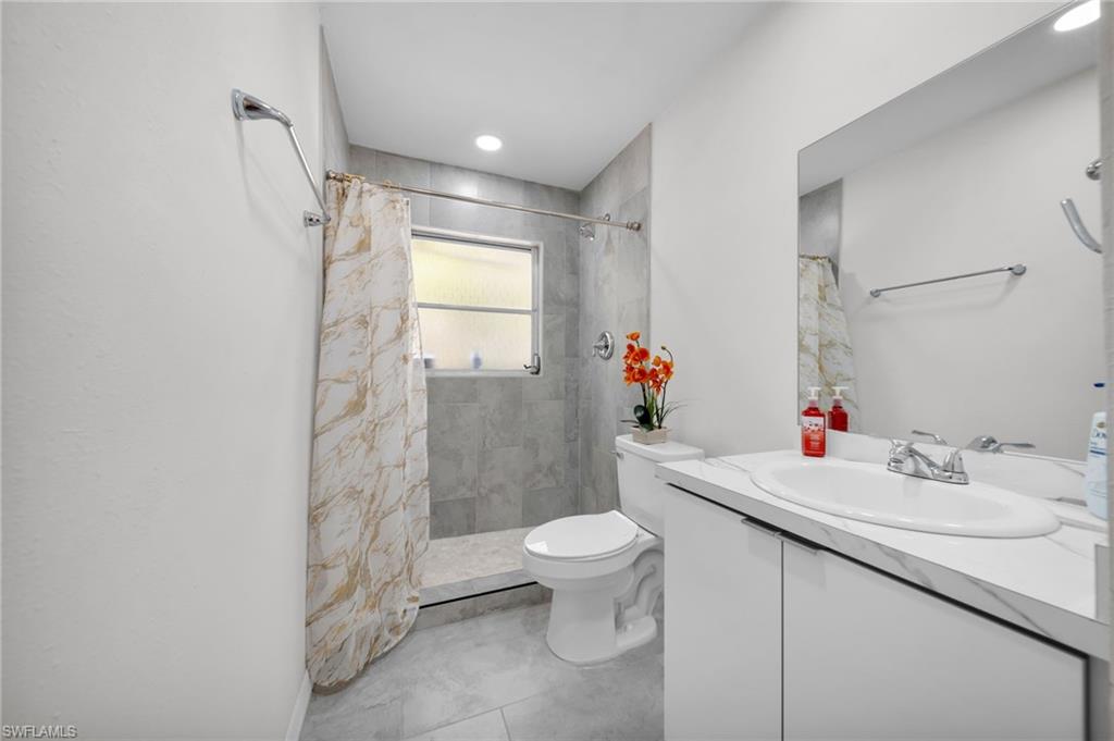 Bathroom with vanity, toilet, and tiled shower