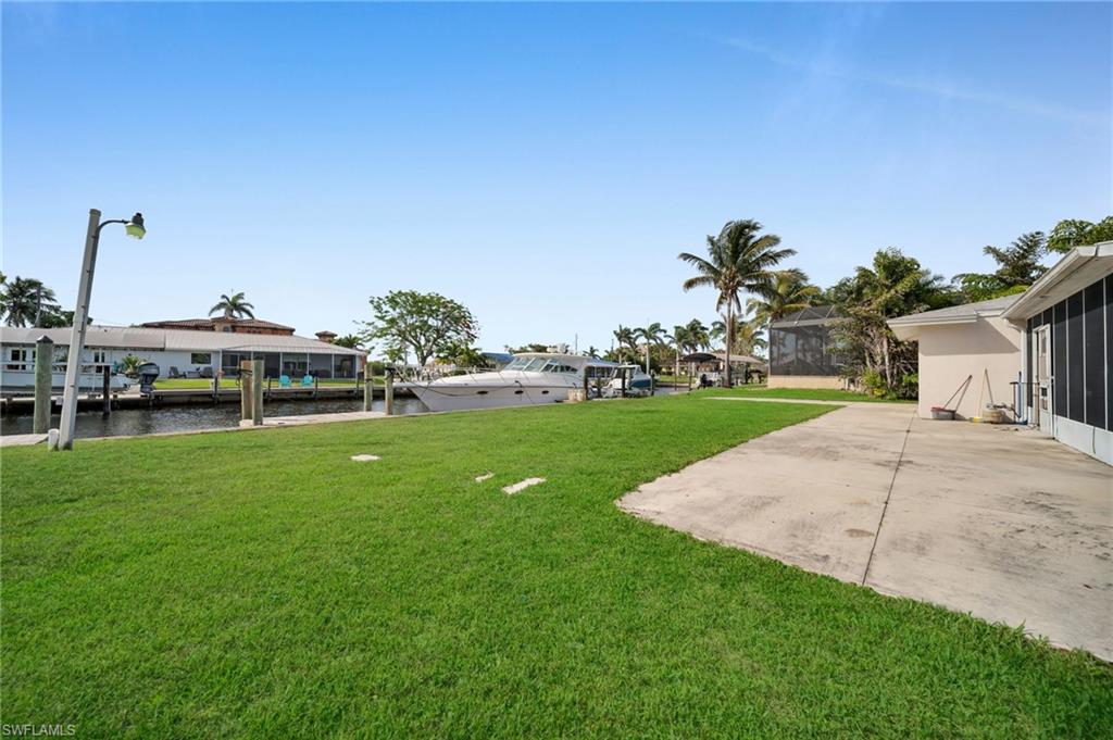 View of grassy yard with a patio area and a water view