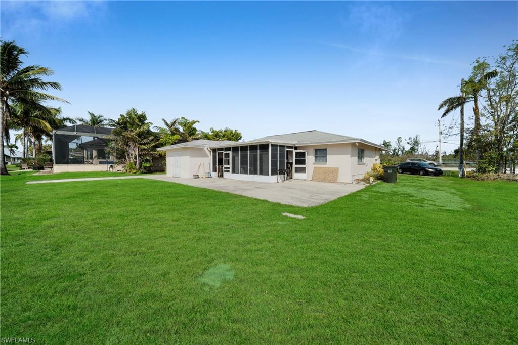Rear view of property with a sunroom, a yard, and a patio