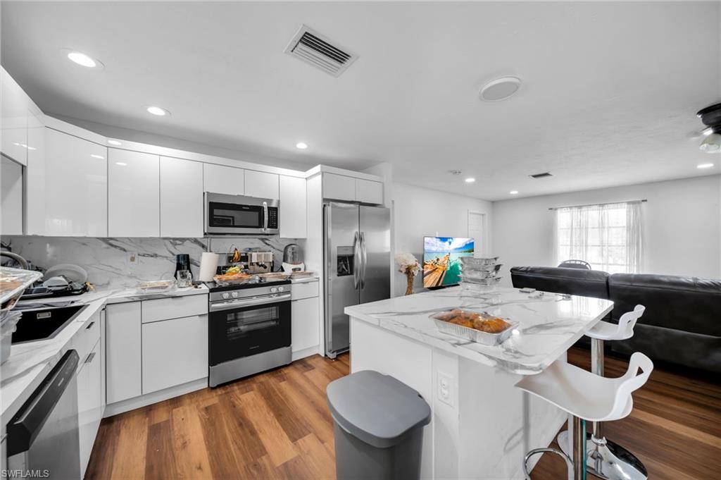 Kitchen featuring stainless steel appliances, a kitchen breakfast bar, modern cabinets, open floor plan, and white cabinets