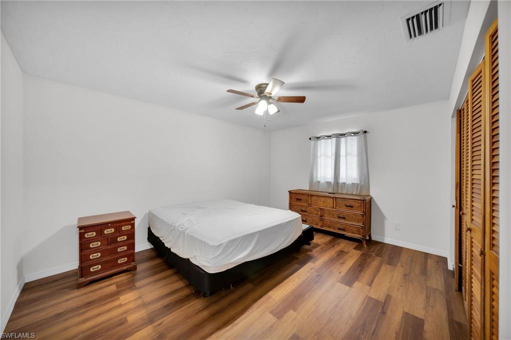 Bedroom with wood finished floors, baseboards, a closet, and ceiling fan