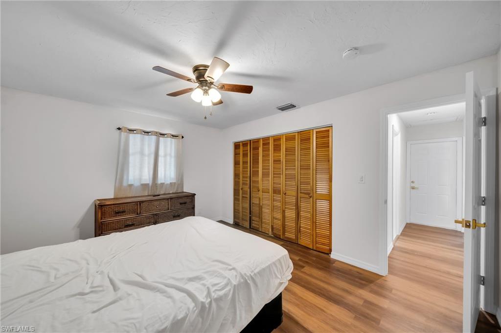 Bedroom with wood finished floors, a closet, baseboards, a ceiling fan, and attic access