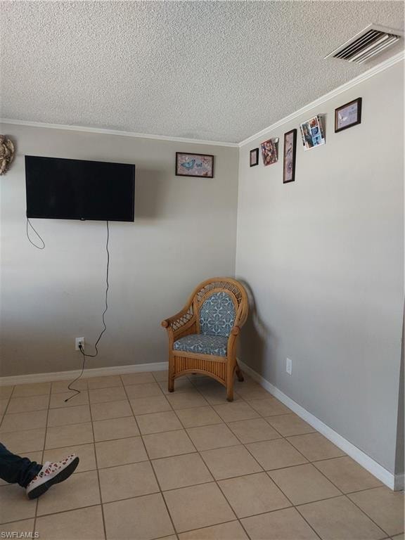 Sitting room with a textured ceiling, ornamental molding, light tile patterned flooring, and baseboards