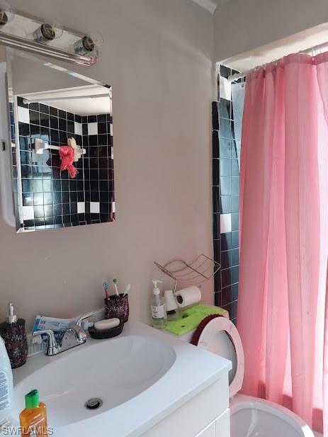 Full bathroom featuring toilet, vanity, and a shower with curtain