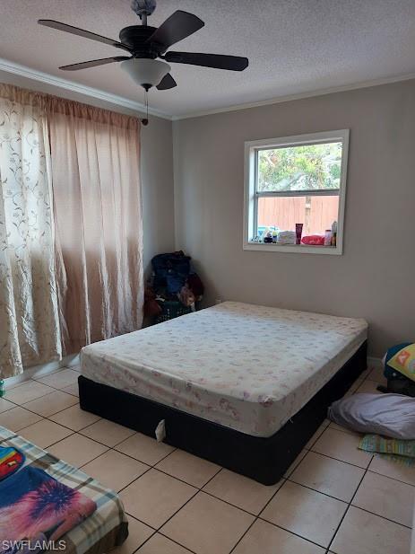 Bedroom featuring crown molding, light tile patterned flooring, a textured ceiling, and a ceiling fan