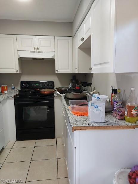 Kitchen with electric range, under cabinet range hood, and white cabinets