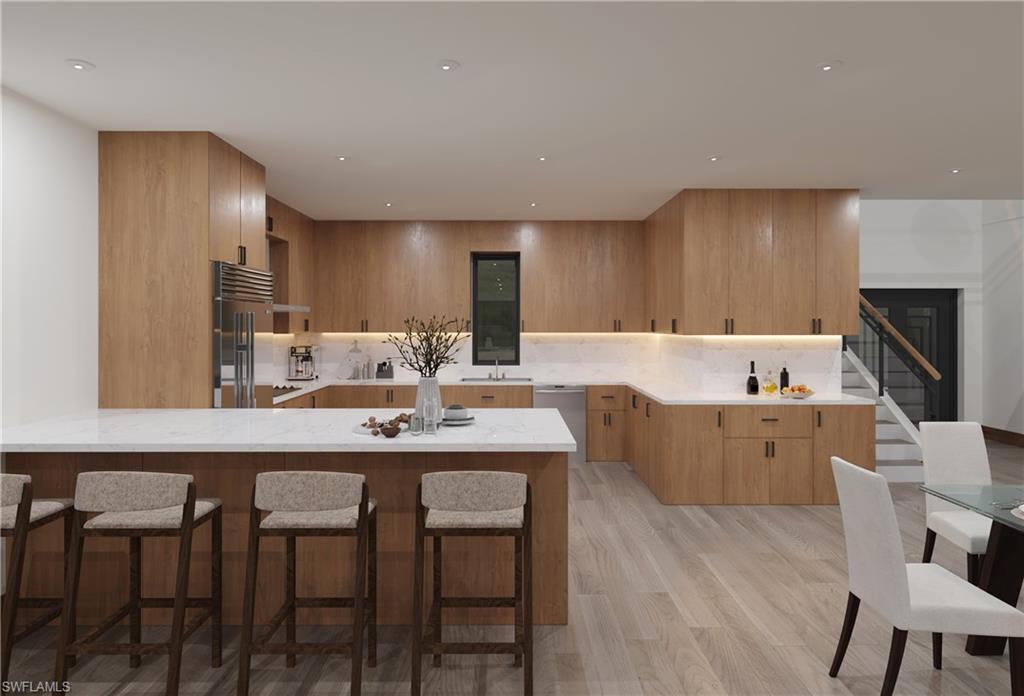 Kitchen with a peninsula, stainless steel appliances, a kitchen breakfast bar, backsplash, and light wood-style floors