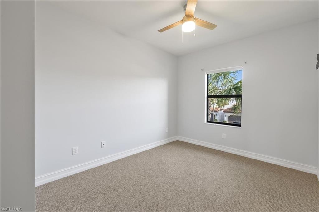 Carpeted spare room featuring a ceiling fan and baseboards