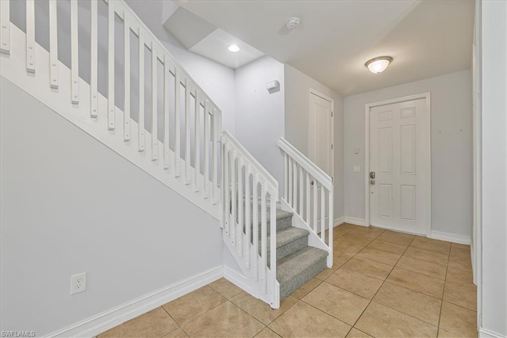 Foyer entrance with stairs, light tile patterned floors, baseboards, and recessed lighting