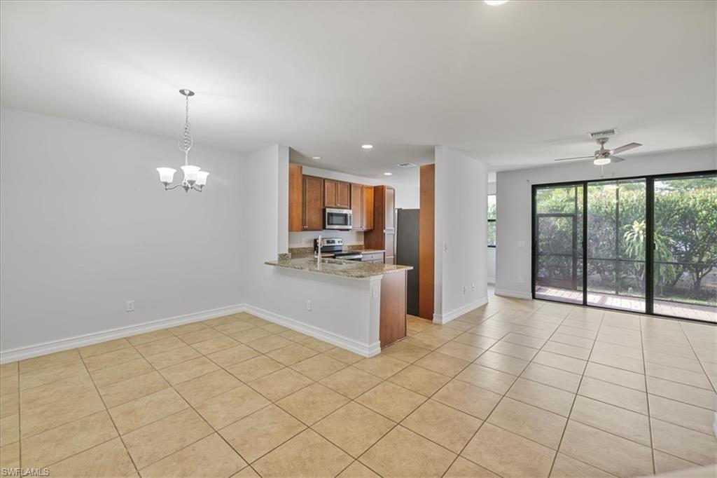 Kitchen with stainless steel appliances, brown cabinetry, light tile patterned floors, baseboards, and recessed lighting