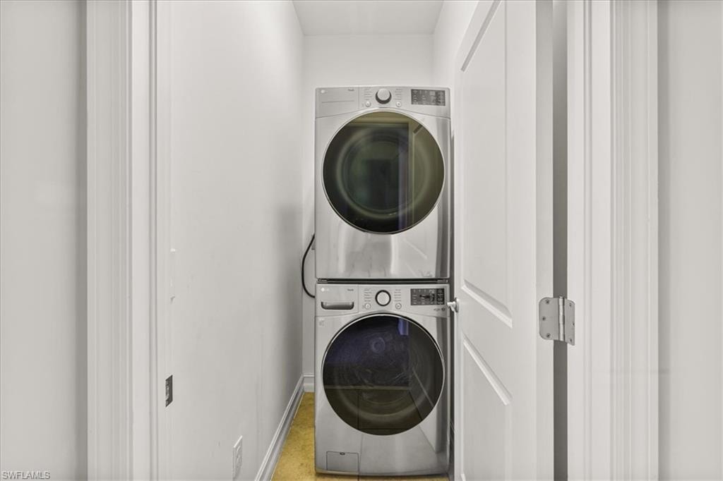Laundry room featuring stacked washer / dryer and baseboards