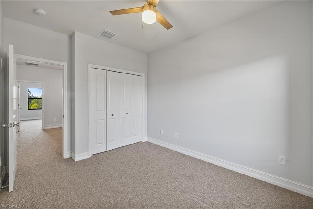 Unfurnished bedroom featuring carpet floors, baseboards, a closet, and ceiling fan