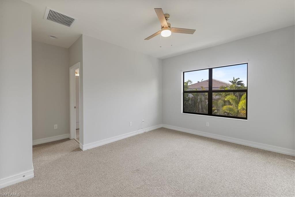 Spare room featuring light carpet, a ceiling fan, and baseboards