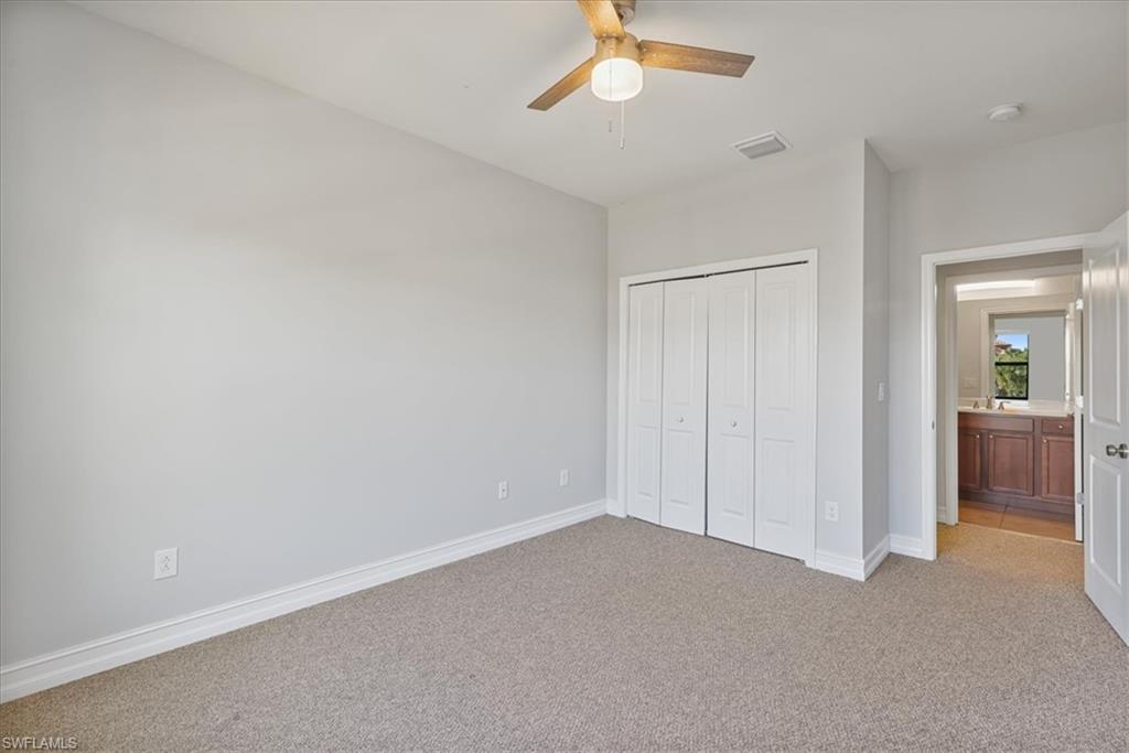 Unfurnished bedroom featuring light colored carpet, a closet, baseboards, and ceiling fan