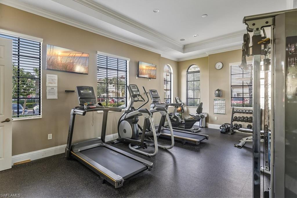 Workout area featuring crown molding, baseboards, a tray ceiling, and recessed lighting