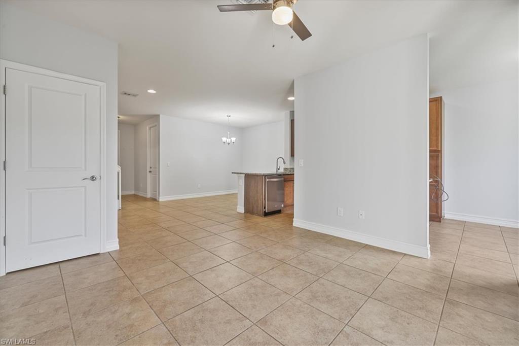 Spare room featuring a ceiling fan, light tile patterned floors, a chandelier, recessed lighting, and baseboards