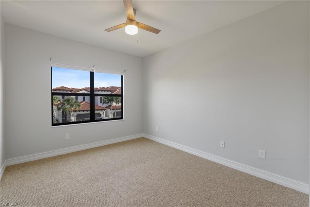 Empty room with light colored carpet, baseboards, and ceiling fan
