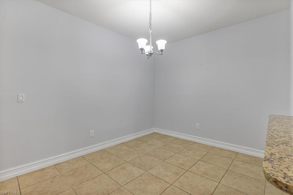 Unfurnished room with baseboards and a chandelier