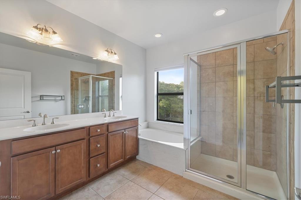 Full bathroom featuring a shower stall, tile patterned floors, double vanity, a bath, and recessed lighting