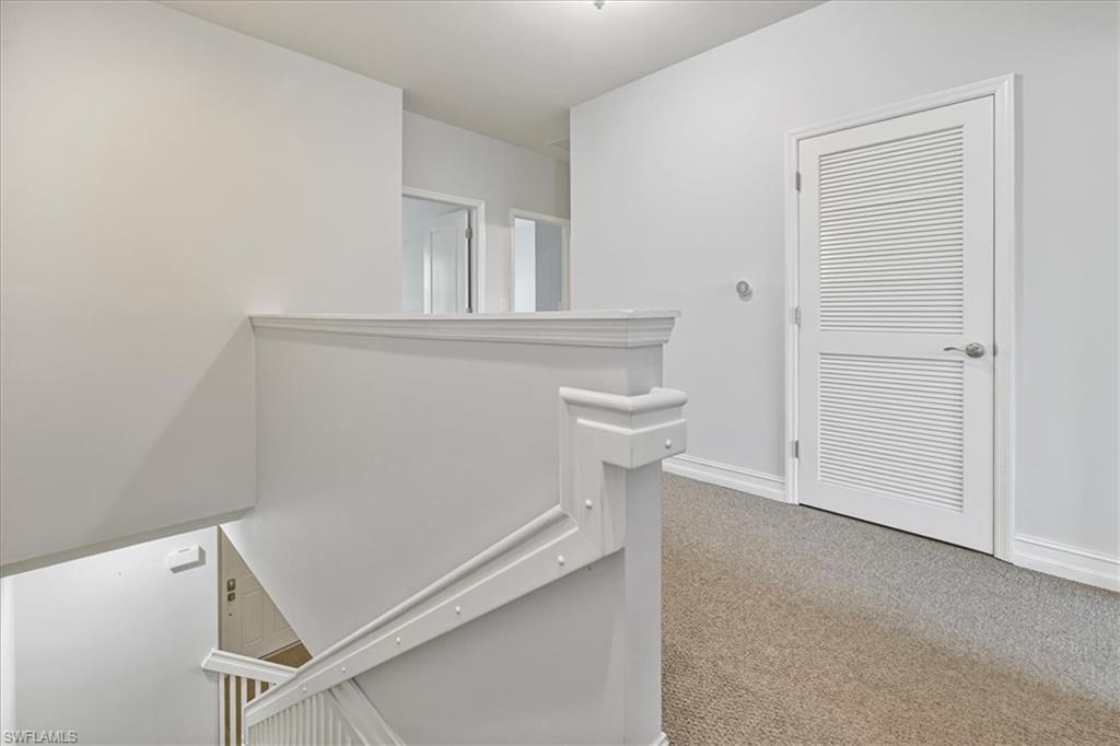 Corridor with carpet floors, baseboards, and an upstairs landing