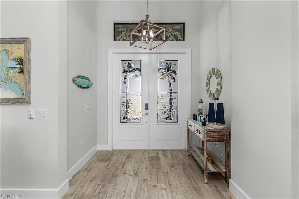 Entrance foyer with french doors, chandelier, and light tile flooring