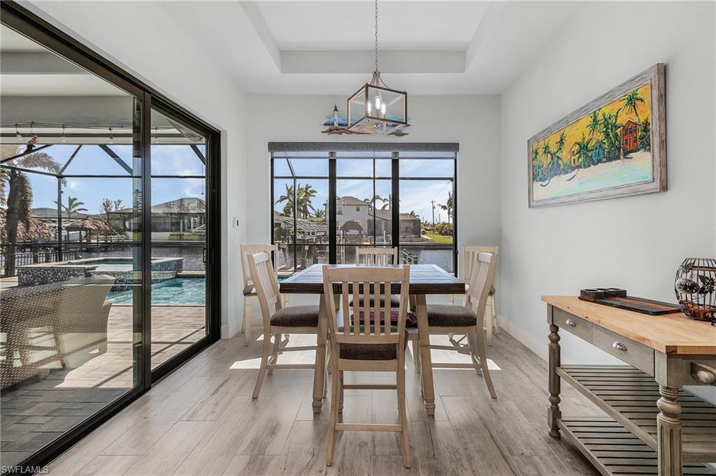 Dining area with light tile flooring, a water view, and a tray ceiling