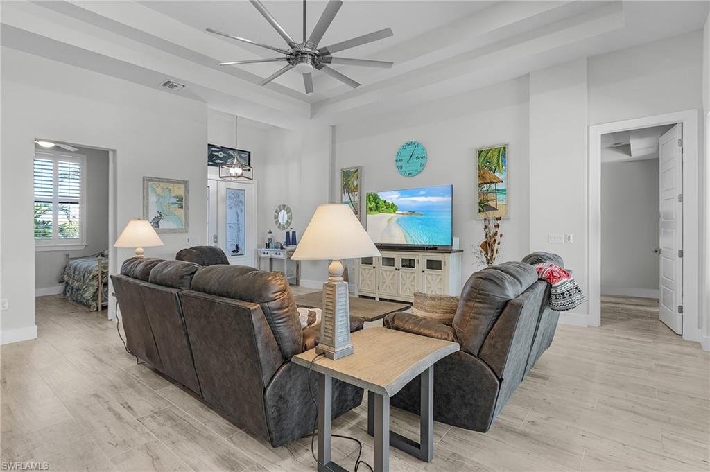 Living room featuring light tile floors, a tray ceiling, and ceiling fan