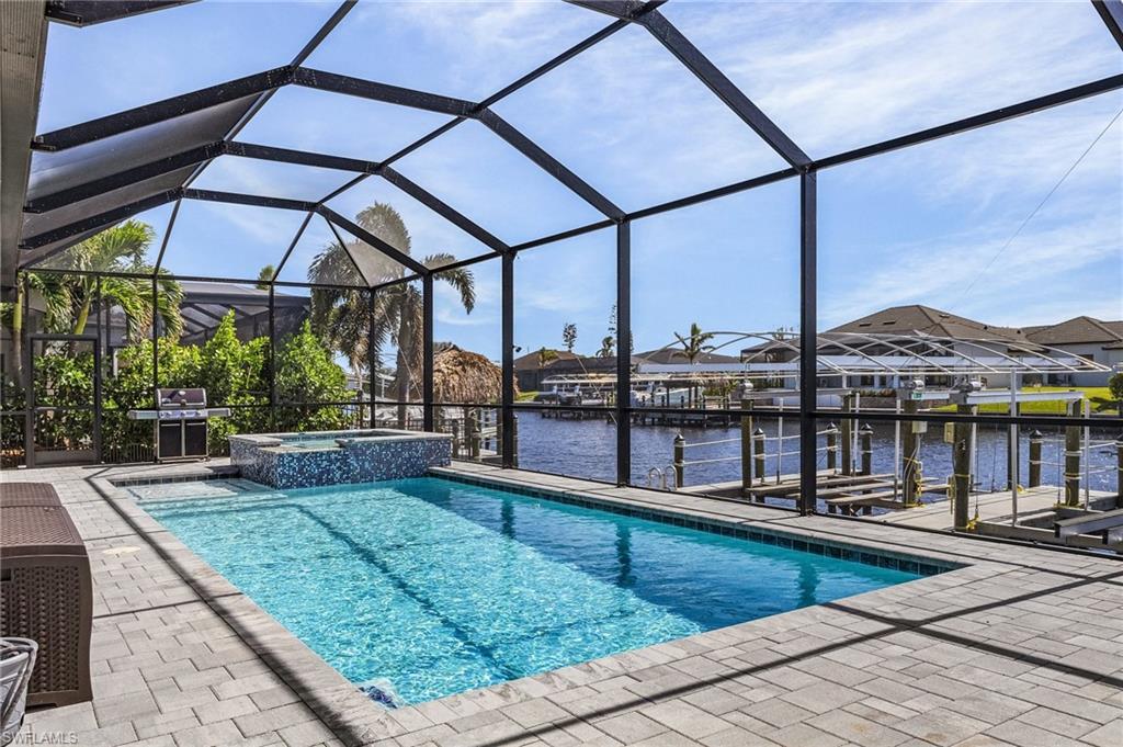 View of pool with a patio, an in ground hot tub, a water view, and a lanai