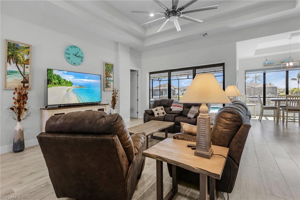Living room with natural light, a high ceiling, light tile flooring, and a raised ceiling