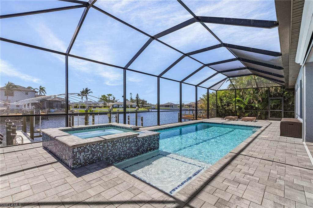 View of pool featuring a patio area, an in ground hot tub, a water view, and a lanai
