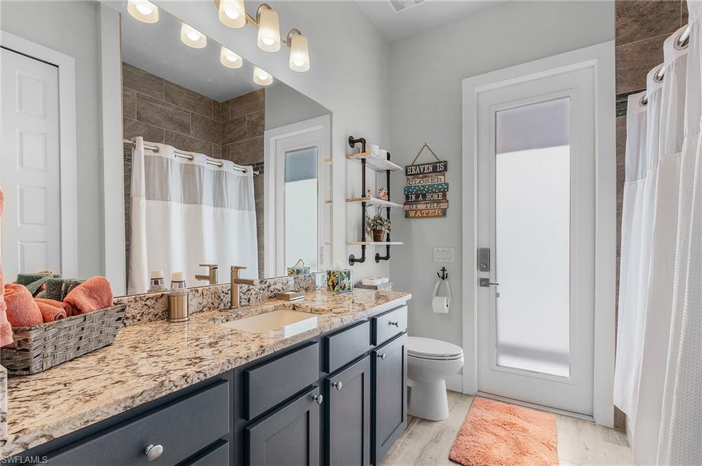 Bathroom with vanity, a shower with shower curtain, tile flooring, and toilet