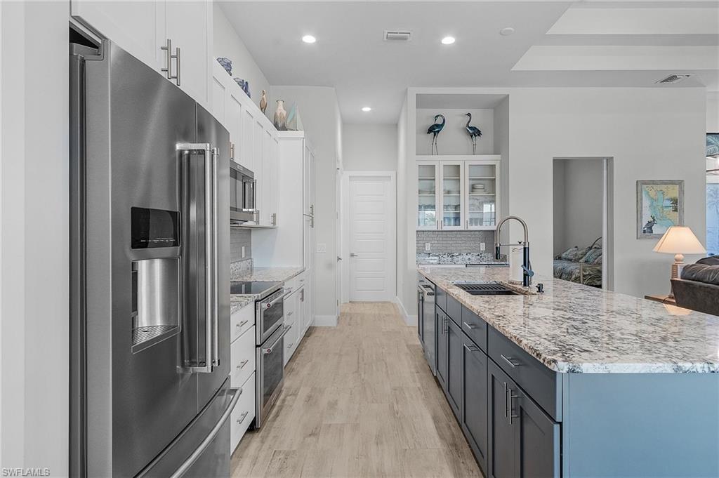 Kitchen with white cabinetry, stainless steel appliances, sink, and light tile type flooring
