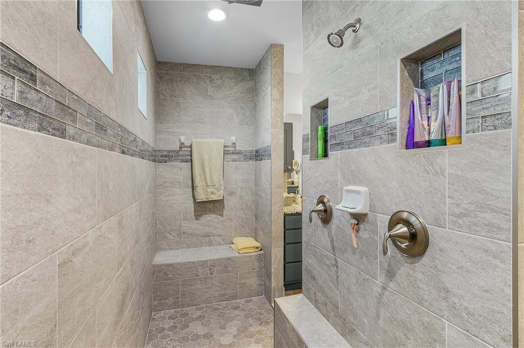 Bathroom featuring vanity, tile walls, and tiled shower