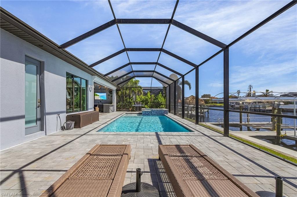 View of swimming pool featuring a patio, a boat dock, a water view, and glass enclosure