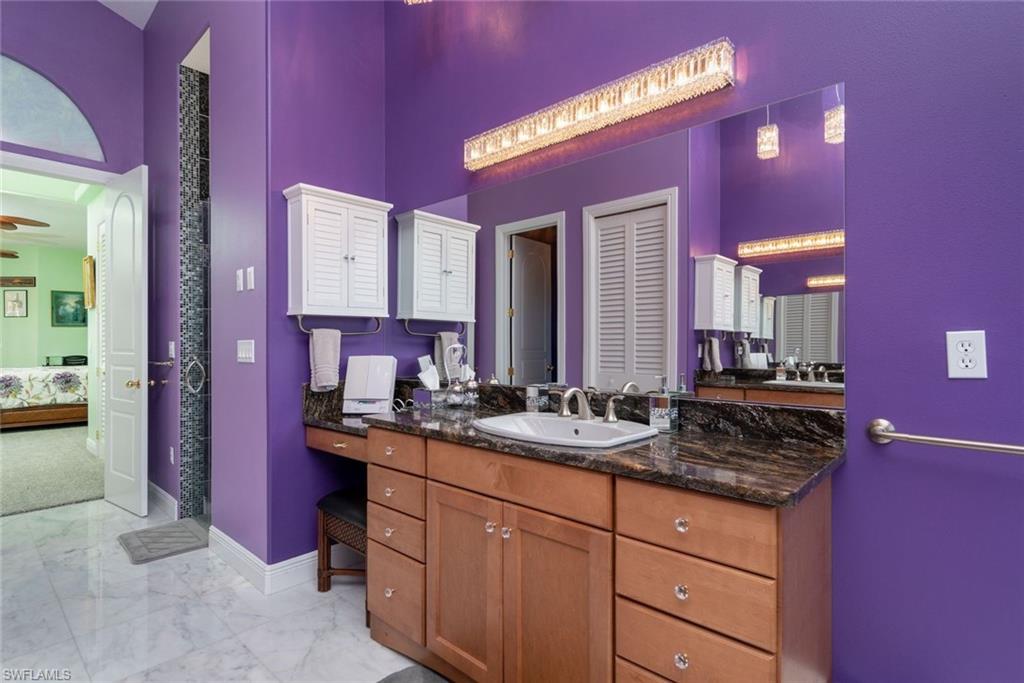 Master Bathroom downstairs with linen closet, dual vanities & sinks, jetted tub, rain shower, private toilet room, marble  flooring, and high vaulted ceiling