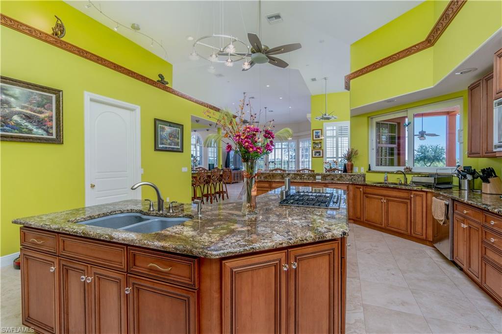 Kitchen featuring double sinks, ceiling fans, stainless steel appliances, a center island with sink, and high vaulted ceiling