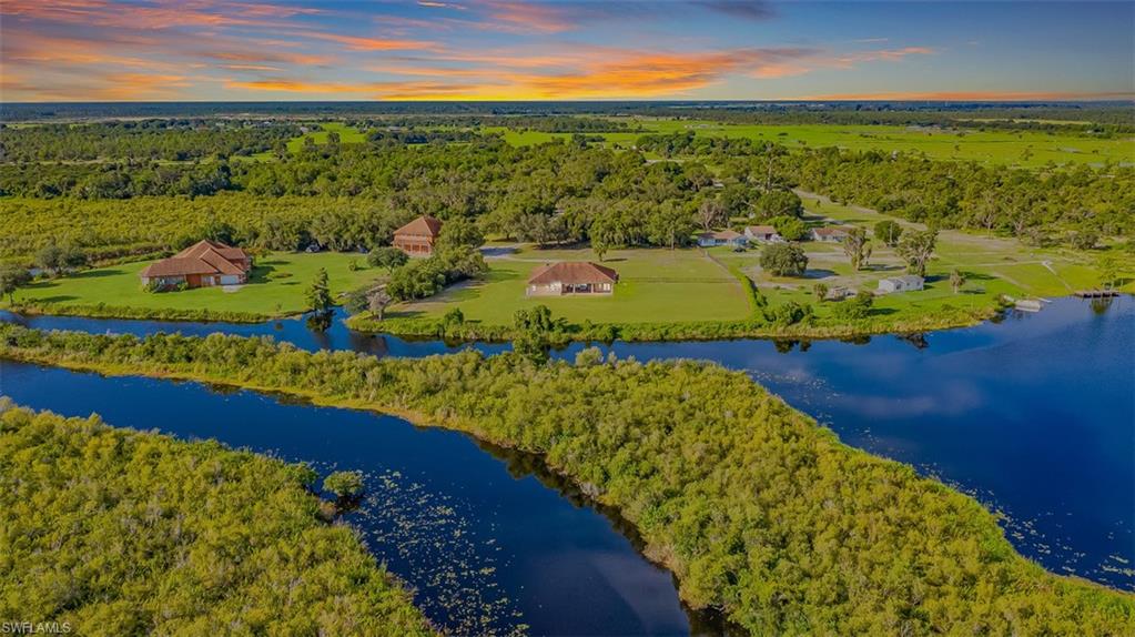Drone / aerial view of a main house, guest house, forest and a large body of water