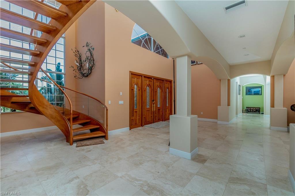 Foyer entrance with stairs, arched walkways, baseboards, and a high ceiling