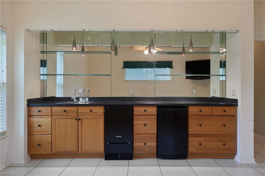 Bathroom with double vanity, toilet, tile patterned flooring, and baseboards