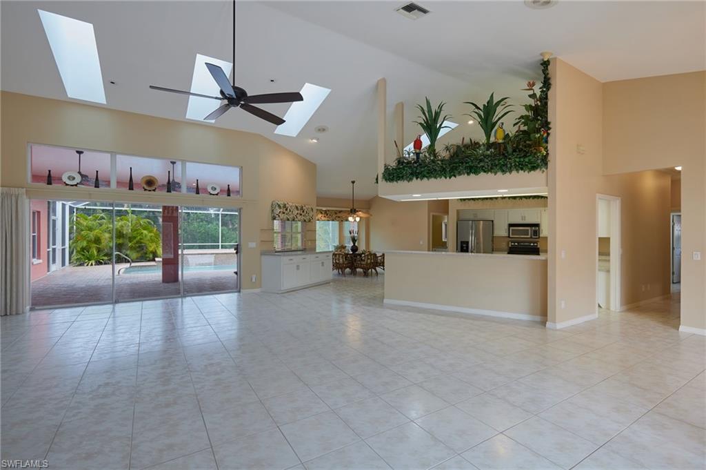 Unfurnished dining area featuring high vaulted ceiling, a chandelier, light tile patterned flooring, and baseboards