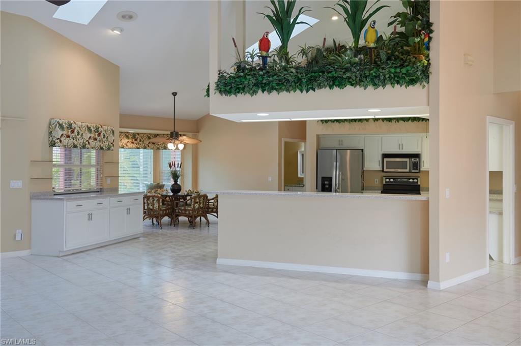 Kitchen featuring appliances with stainless steel finishes, a sink, a peninsula, white cabinetry, and light tile patterned floors