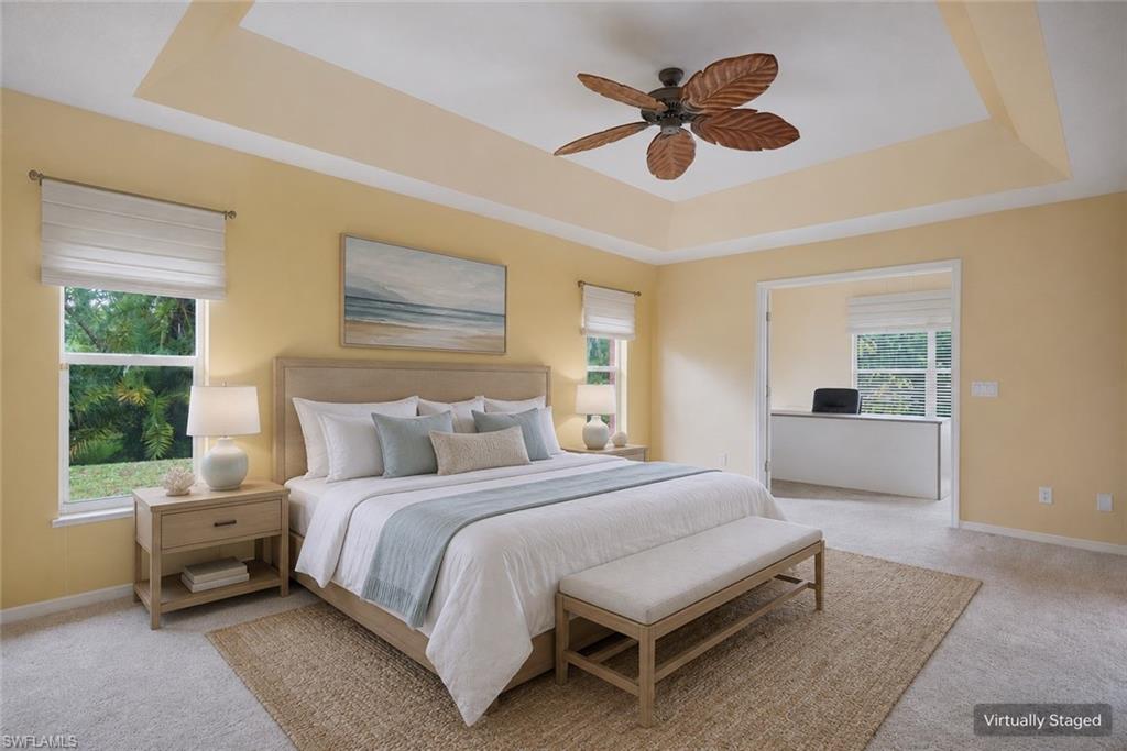 Carpeted spare room with ceiling fan, baseboards, and a tray ceiling