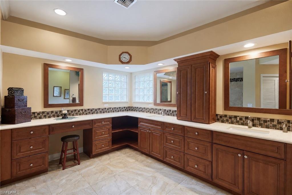Kitchen featuring a sink, brown cabinetry, baseboards, and dark stone countertops