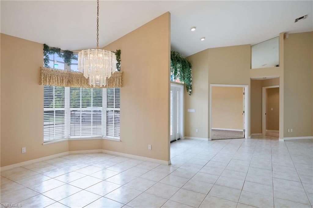 Kitchen featuring appliances with stainless steel finishes, high vaulted ceiling, a skylight, light tile patterned flooring, and decorative light fixtures
