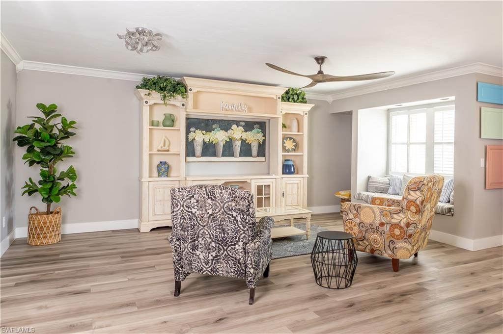 Sitting room featuring ornamental molding, a ceiling fan, baseboards, and light wood-type flooring