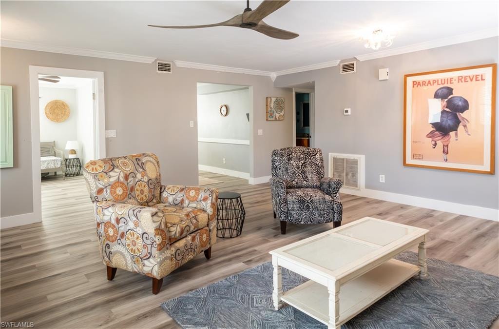 Living area featuring ornamental molding, light wood-style floors, a ceiling fan, and baseboards