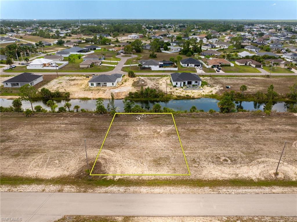 Aerial view of residential area with property parcel outlined and a nearby body of water