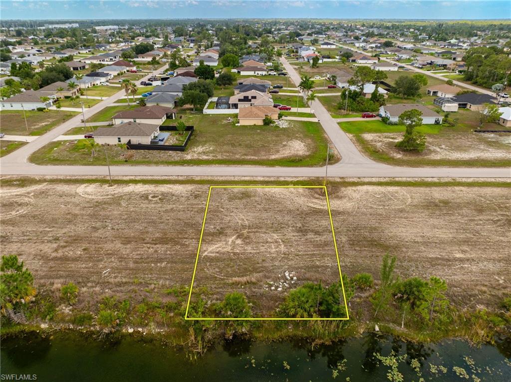 Aerial view of residential area with property boundaries highlighted and a nearby body of water