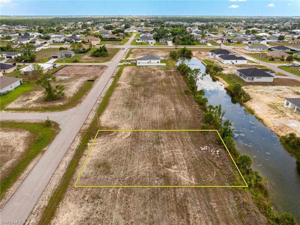 Aerial view of residential area featuring property parcel outlined and a nearby body of water